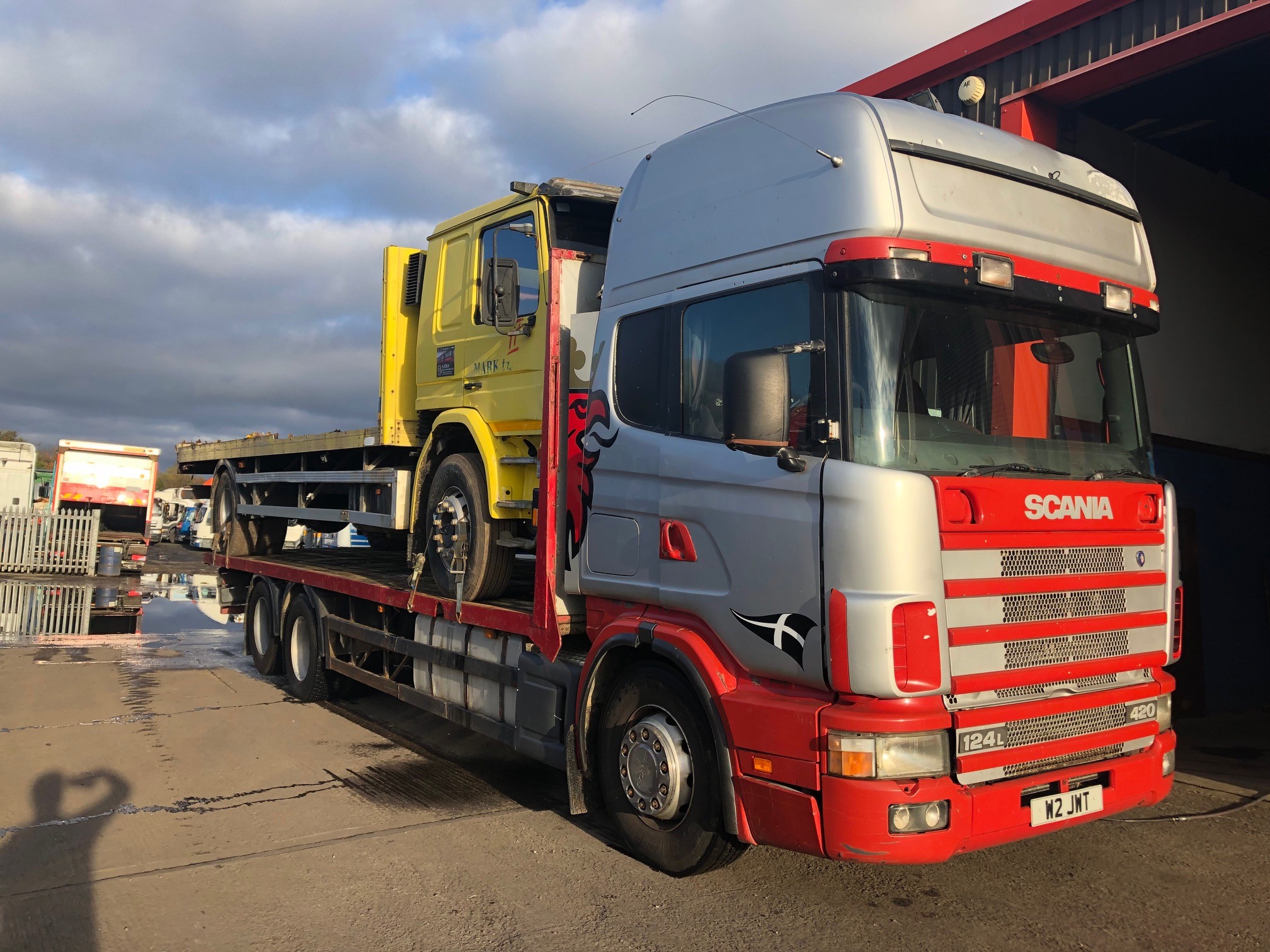 Silver truck carrying yellow truck